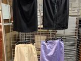 three pairs of skirts hanging on a wire rack in a store
