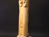 a wooden statue of a woman holding a child on a rock
