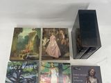 four books are sitting on a white surface next to a black box