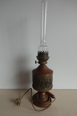 une lampe à huile à l'ancienne posée sur une table, avec un mur blanc en arrière-plan