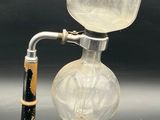a glass cup with a wooden handle on a metal stand