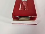 an open red box on a white surface with a small piece of paper