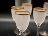 four wine glasses sitting on a table with a bottle in the background