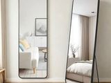 un grand miroir posé par terre à côté d'un lit