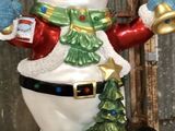 un bonhomme de neige qui tient une clochette et un sapin de Noël