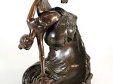 bronze statue of a woman on a rock with a bird in her hand