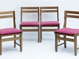 quatre chaises en bois avec des coussins roses sont alignées sur une surface blanche