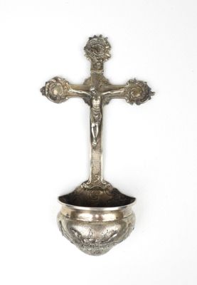 une croix en argent posée sur un bol en argent, le tout sur un fond blanc