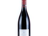 the bottle of red wine is sitting on a white surface