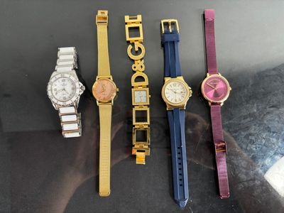 four watches are lined up in a row on a table