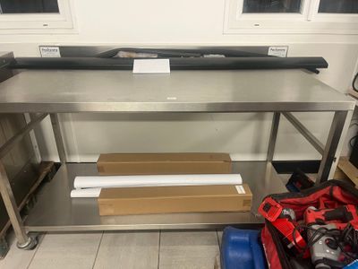 une grande table de travail en acier inoxydable équipée d'une étagère