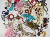 a pile of assorted necklaces and bracelets on a white surface