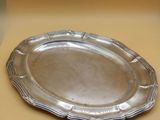 a silver plate sitting on a table next to a vase