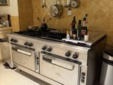 a kitchen with a stove, oven, and a trash can