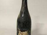 une vieille bouteille de vin posée sur une table blanche