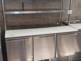 a stainless steel counter with two sinks and a refrigerator