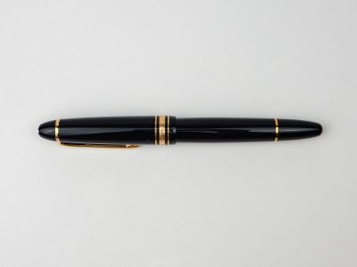 un stylo plume noir et doré posé sur une surface blanche