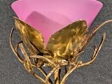 a gold vase with a pink glass in it