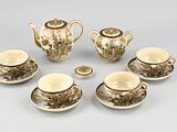 five cups and saucers and a teapot on the table