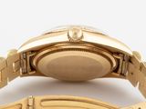 a close up of a watch on a gold bracelet on a white surface