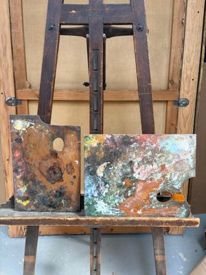 un chevalet en bois sur lequel est posé un tableau, devant un autre chevalet en bois