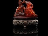 une figurine en jade rouge sculptée représentant un homme et une femme sur un bateau