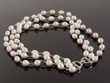 a white pearl and emerald necklace on a black surface