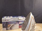 une boîte et un fer à repasser posés sur une table, sur fond noir