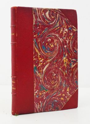 un vieux livre à la couverture rouge posé sur une table blanche