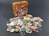 a suitcase full of buttons on a table next to a pile of them