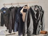 a lot of jackets hanging on a rack in a room