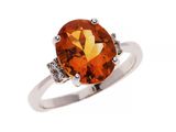 un gros plan d'une bague sertie d'une pierre orange et de diamants