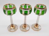 three green glass goblets sitting on top of a white table