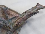 a bronze statue of a person laying on a tree branch