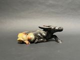 a figurine of a cow laying down on the ground