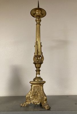 un bougeoir ancien en laiton sur lequel est posée une bougie, posé sur une table