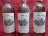 trois bouteilles de vin sont alignées sur un fond rouge
