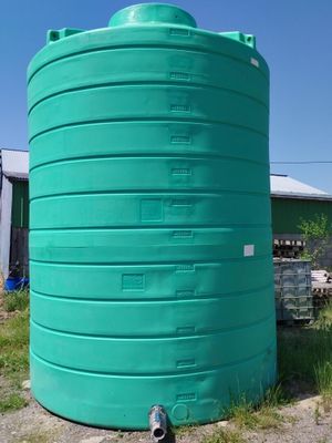 a large green water tank sitting in the middle of a field