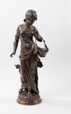 une statue antique en bronze représentant une femme tenant un panier de fleurs