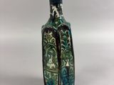 a small blue and green vase with a black handle