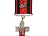 une image représentant une médaille ornée d'une croix, suspendue à un ruban rouge et noir