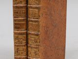 two old books sitting on top of each other on a white surface