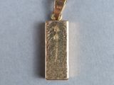 gros plan d'un pendentif en or sur une surface blanche