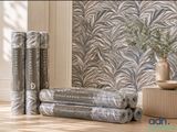 plusieurs rouleaux de papier peint posés sur un parquet, à côté d'un vase
