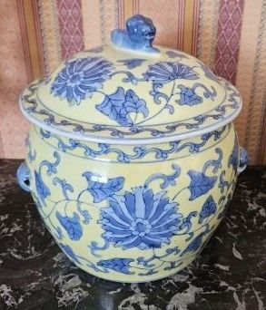 un vase jaune et bleu muni d'un couvercle, posé sur une table
