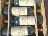 six bottles of wine in a wooden box on a table