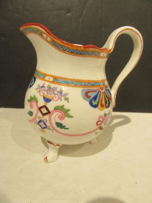 a white pitcher with colorful designs on it on a table