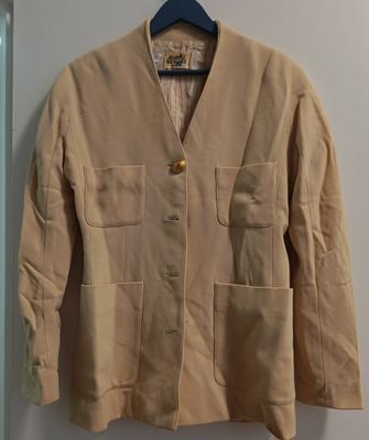 une veste beige suspendue à un cintre devant un mur blanc