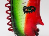 a red and green vase with a face on it