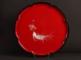 une assiette rouge décorée d'un oiseau et de fleurs